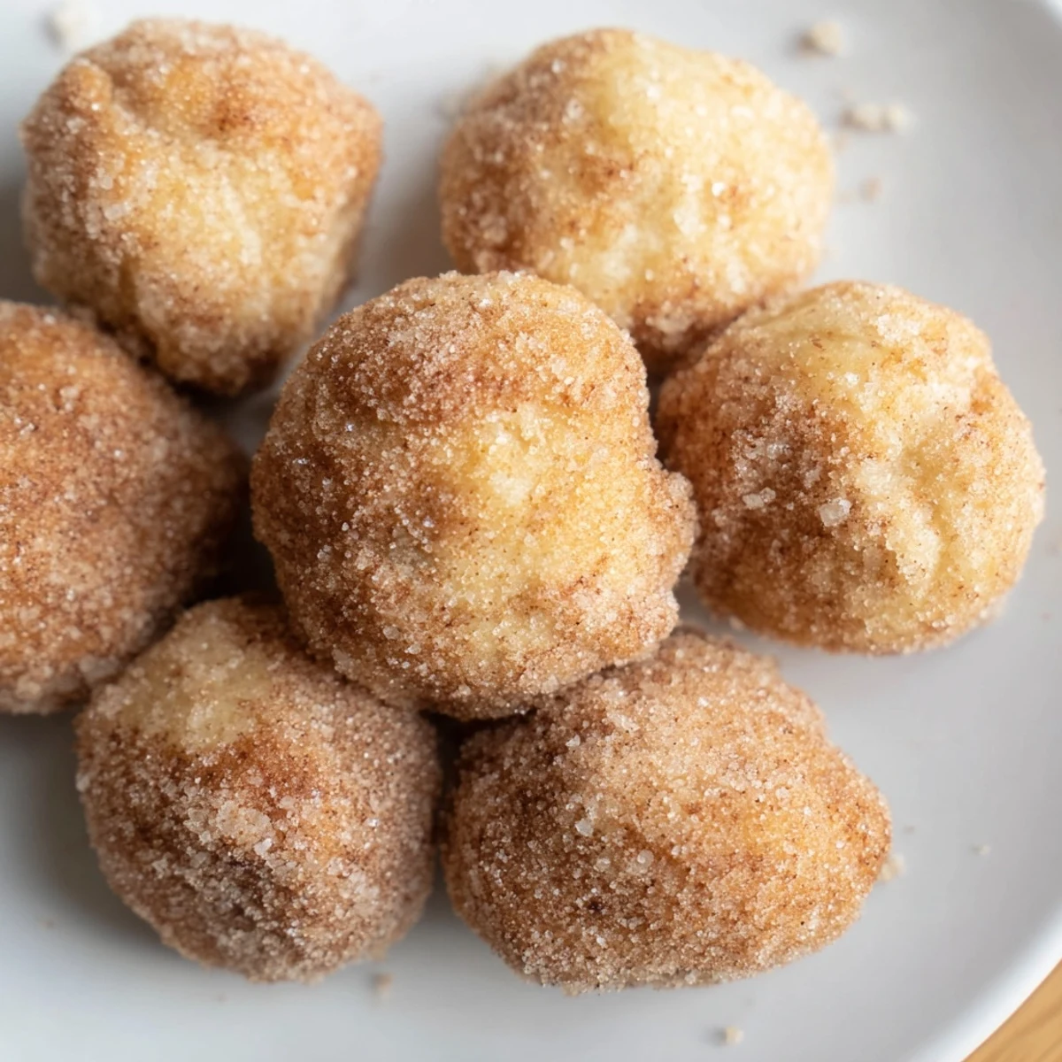 Close-up of warm, freshly rolled cinnamon sugar donut holes, perfect for a quick breakfast treat.