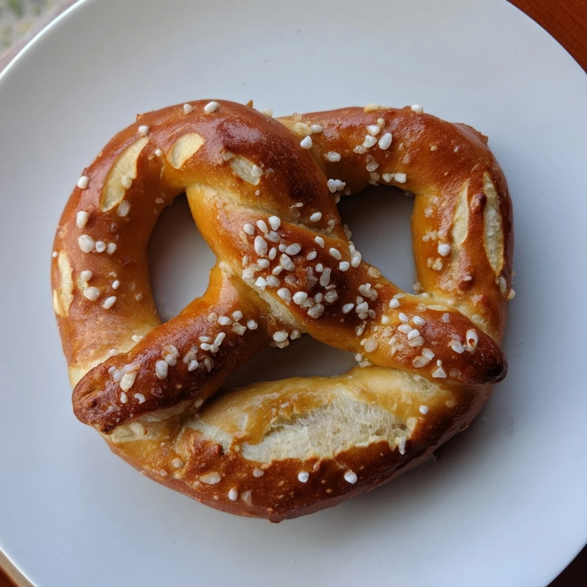 Golden-brown soft pretzels, slightly salted and glistening, ready to eat with a creamy dipping sauce.