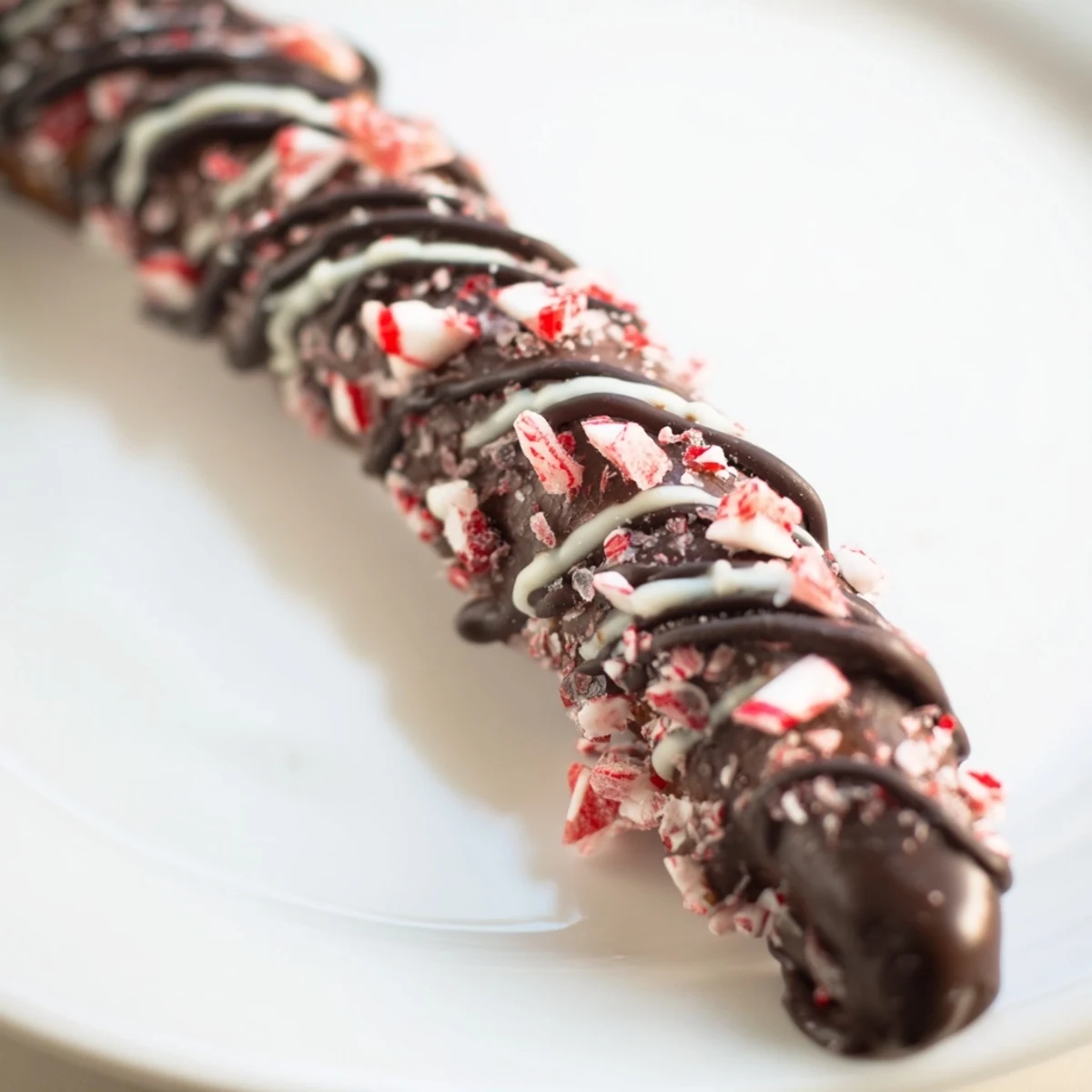 A close-up of Dark Chocolate Peppermint Bark Pretzels, highlighting the rich dark chocolate contrasted with sharp white drizzle and crushed peppermint, perfect for holiday platters.