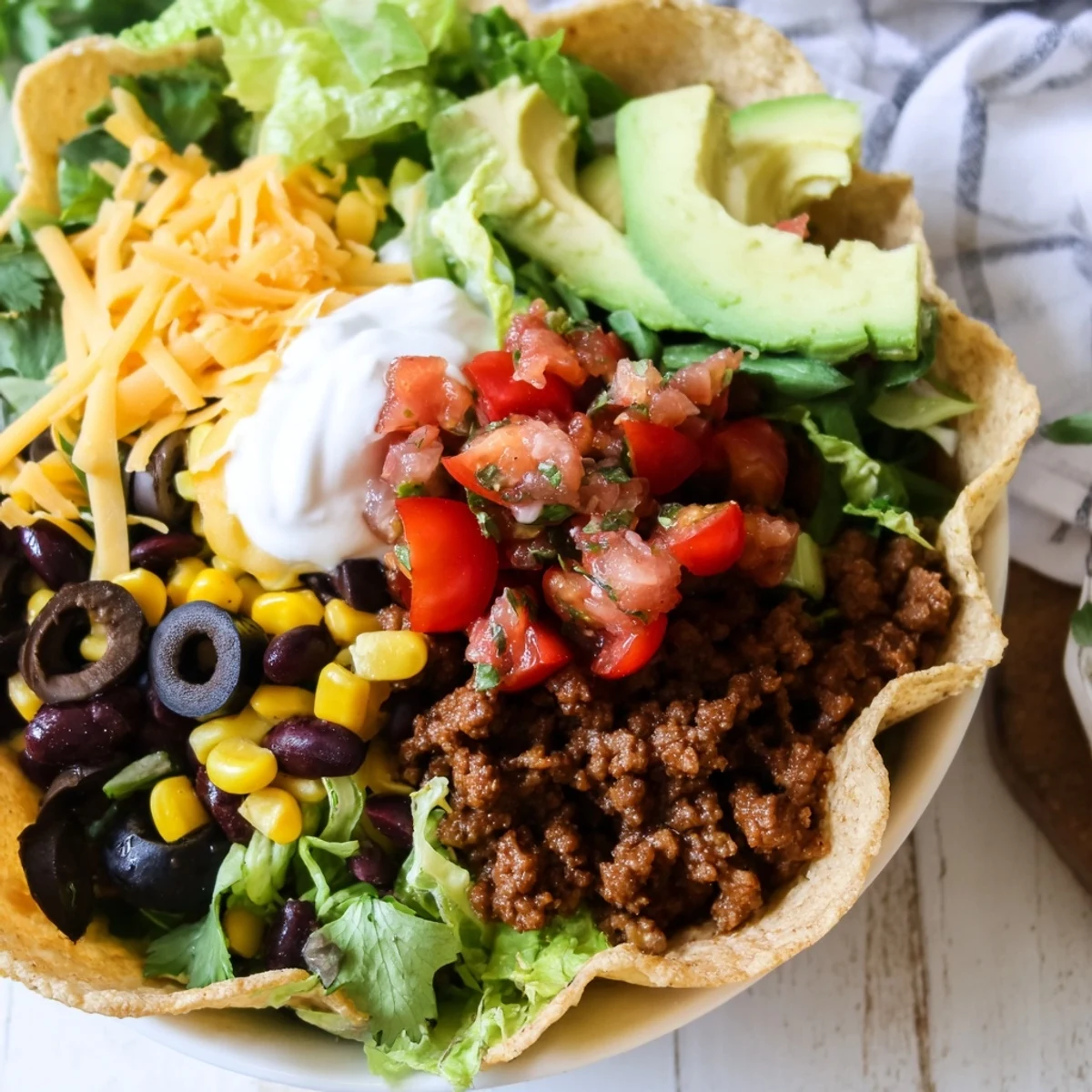 Crisp golden tortilla bowl stuffed with seasoned ground beef, fresh salsa, and creamy avocado toppings.