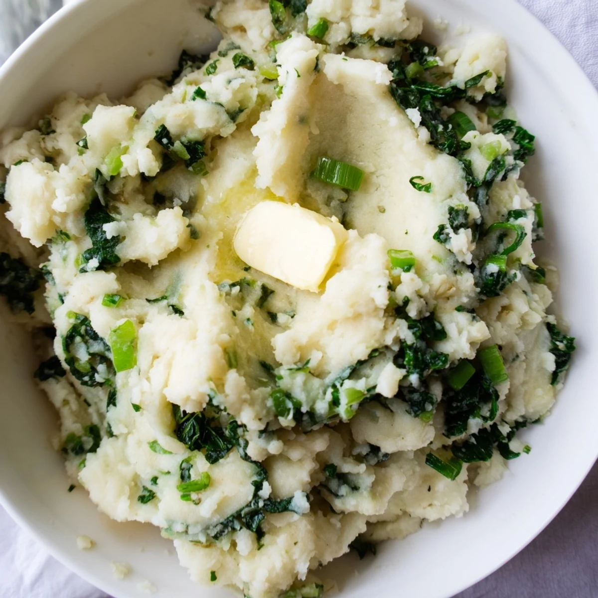 Creamy Irish Colcannon mashed potatoes with kale and scallions, topped with melting butter in a rustic serving bowl.