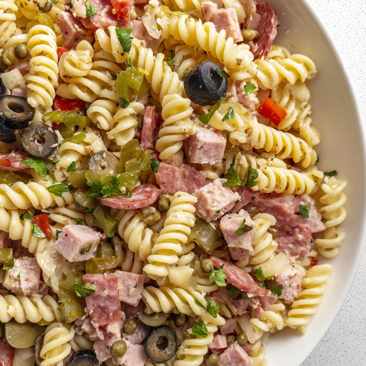 Colorful New Orleans Muffuletta Pasta Salad in a bowl, featuring crunchy giardiniera, roasted red peppers, and briny olives, ready to serve cold.
