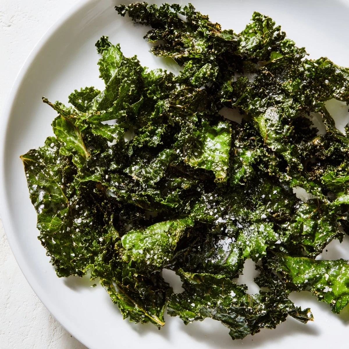 Freshly baked Green Kale Chips with Sea Salt are arranged in a crispy, single layer on a baking sheet.