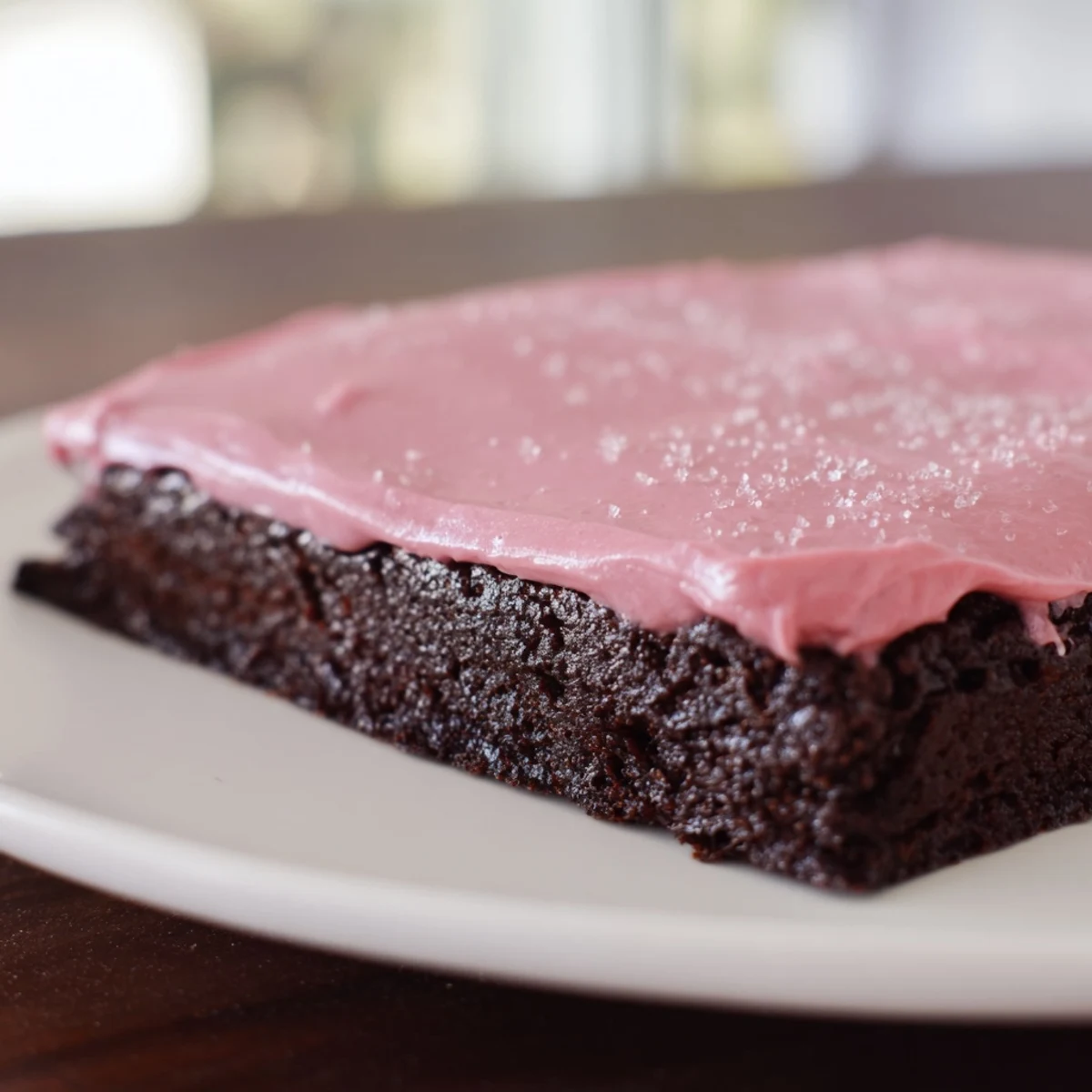 Moist, fudgy brownies with pink frosting on a dessert platter, ready for a party.