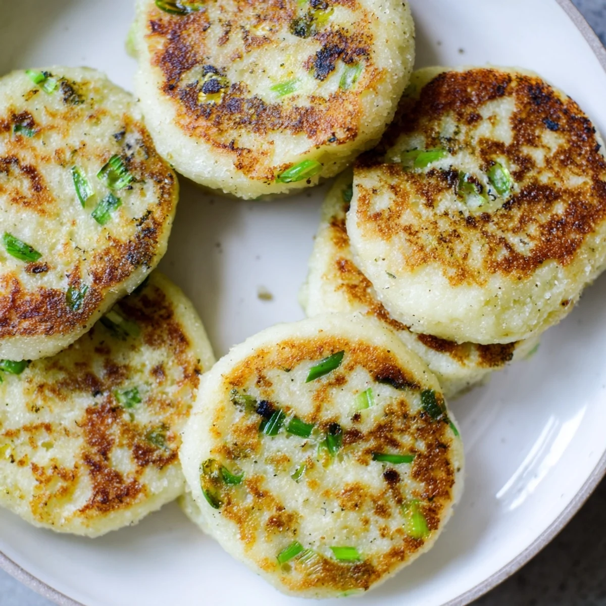 Freshly fried Irish potato cakes with scallions on a plate, golden brown and ready to serve with melted butter.  