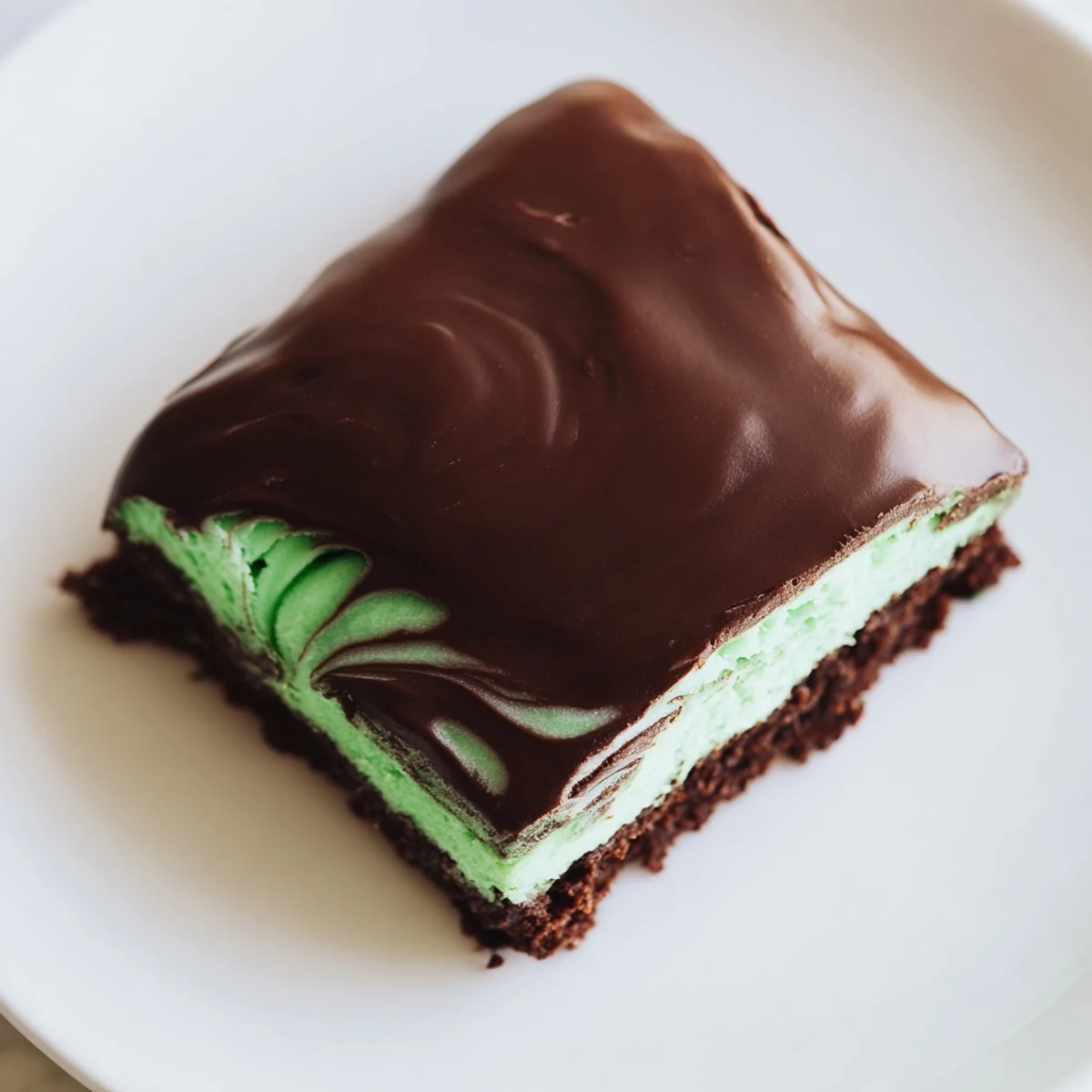 Fudgy Green Mint Brownies topped with a glossy chocolate glaze, cut into neat squares on a marble slab.