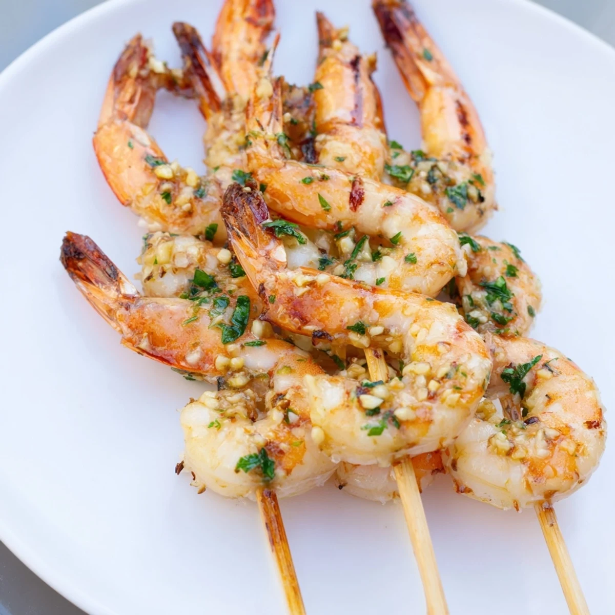 Golden grilled Lemon Garlic Shrimp Skewers with Parsley sizzle with fresh lemon wedges on a plate.