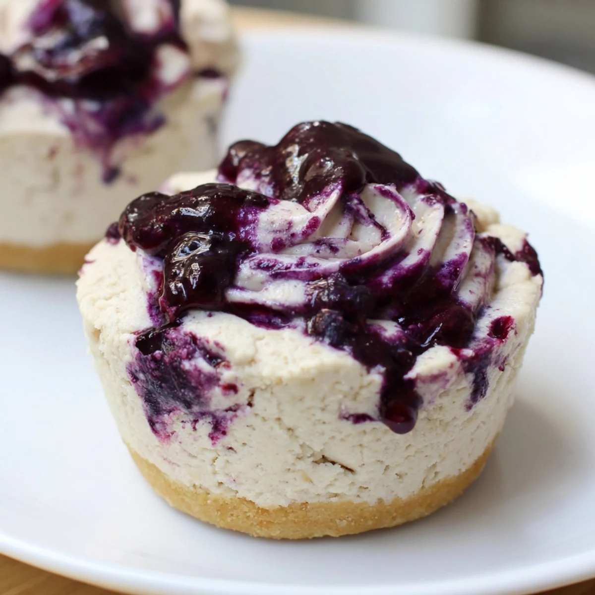 Freshly chilled Blueberry Cheesecake Protein Bites with a creamy swirl and graham cracker base on a marble board.