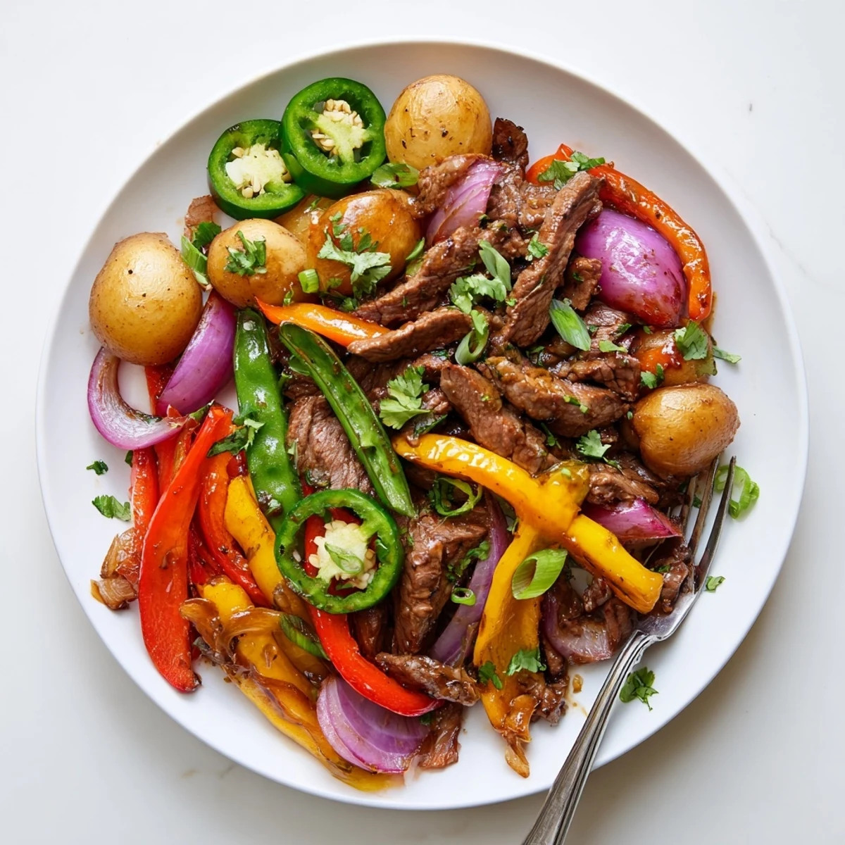 Hearty Blackstone Cowboy Stir Fry Dinner is plated with golden potatoes and fresh cilantro garnish. 