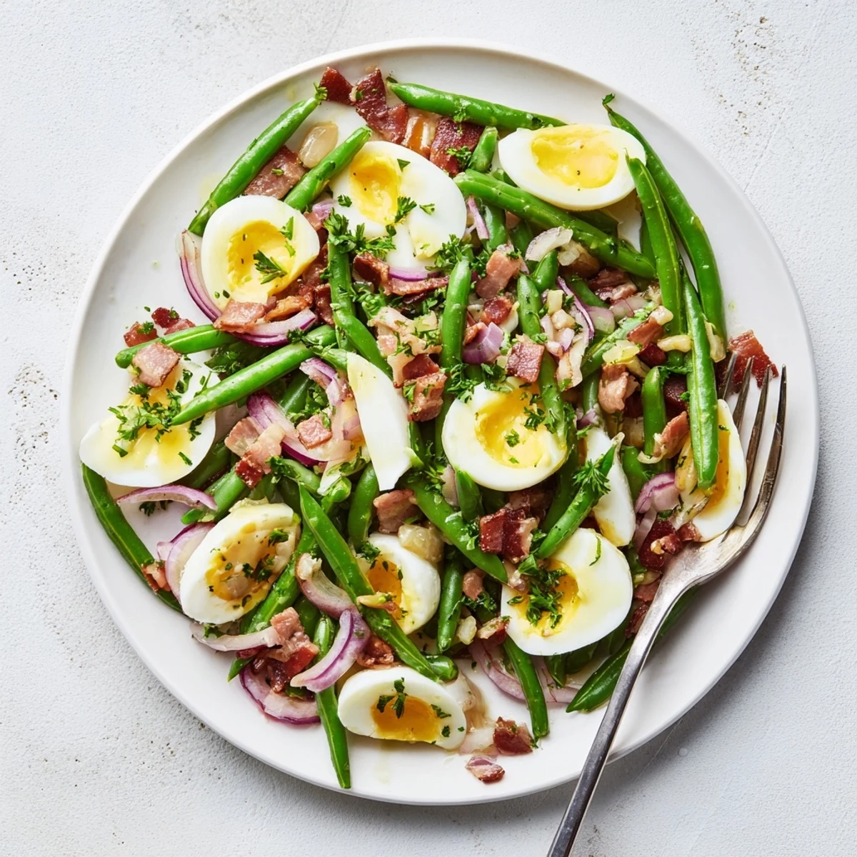 The vibrant Green Bean, Bacon, and Egg Salad features bright green beans, smoky bacon, and golden eggs tossed with a tangy vinaigrette.