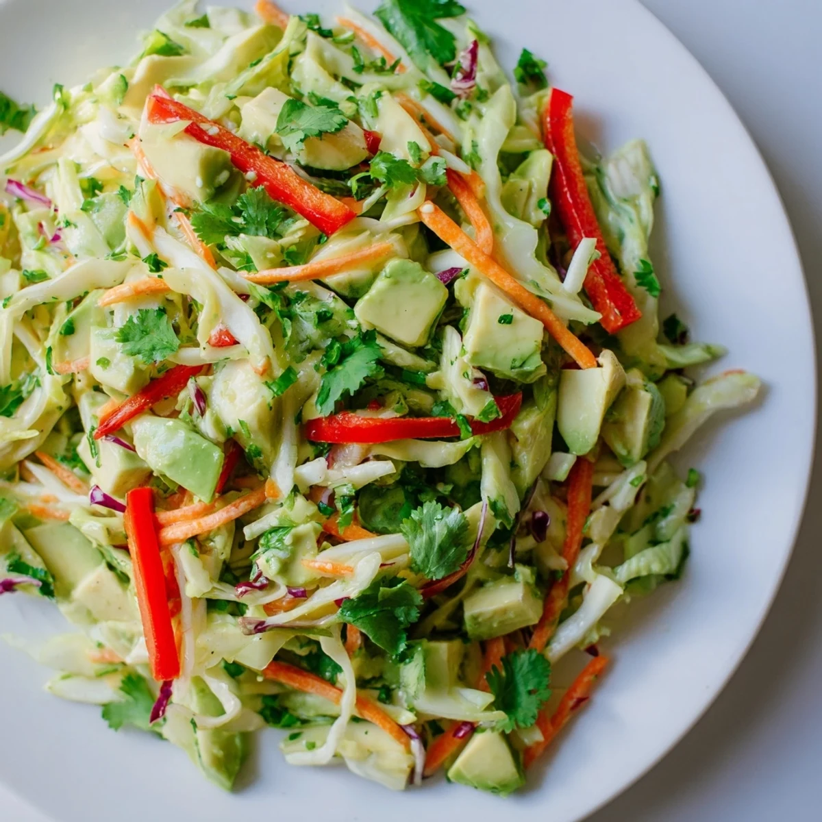 A serving of Avocado Cabbage Salad showcases a lime-dressed mix of green and red cabbage, finished with sesame seeds.