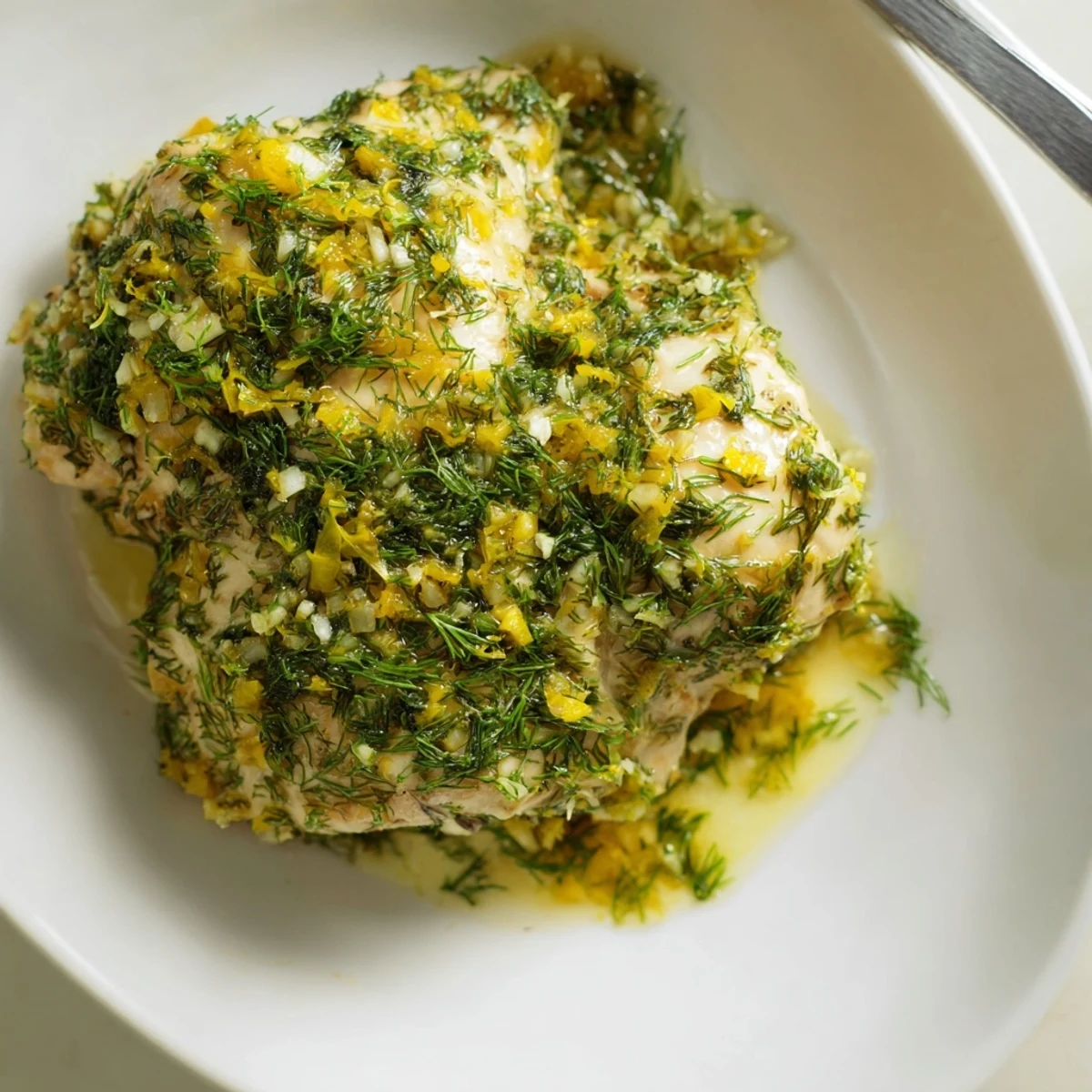 Tender paleo lemon dill chicken fresh from the oven, garnished with lemon slices and chopped dill on a platter.