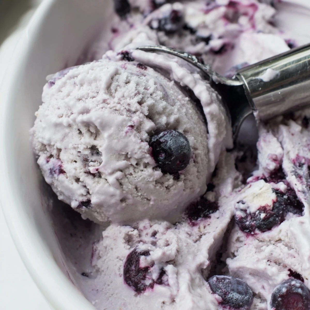 Homemade Blueberry Cottage Cheese Ice Cream being scooped from a freezer container, showing its smooth texture and rich berry color.