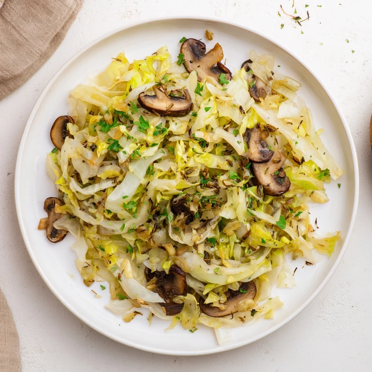 Steaming Vegetarian Cabbage Mushroom Sauté served in a white bowl, garnished with fresh parsley and a lemon wedge on the side.