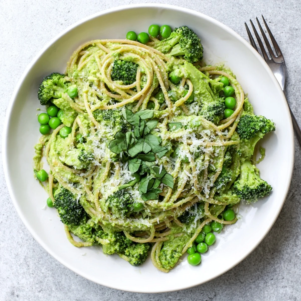 A close-up of Veggie Smuggler Avocado Pasta twirled on a fork, showing rich green sauce.