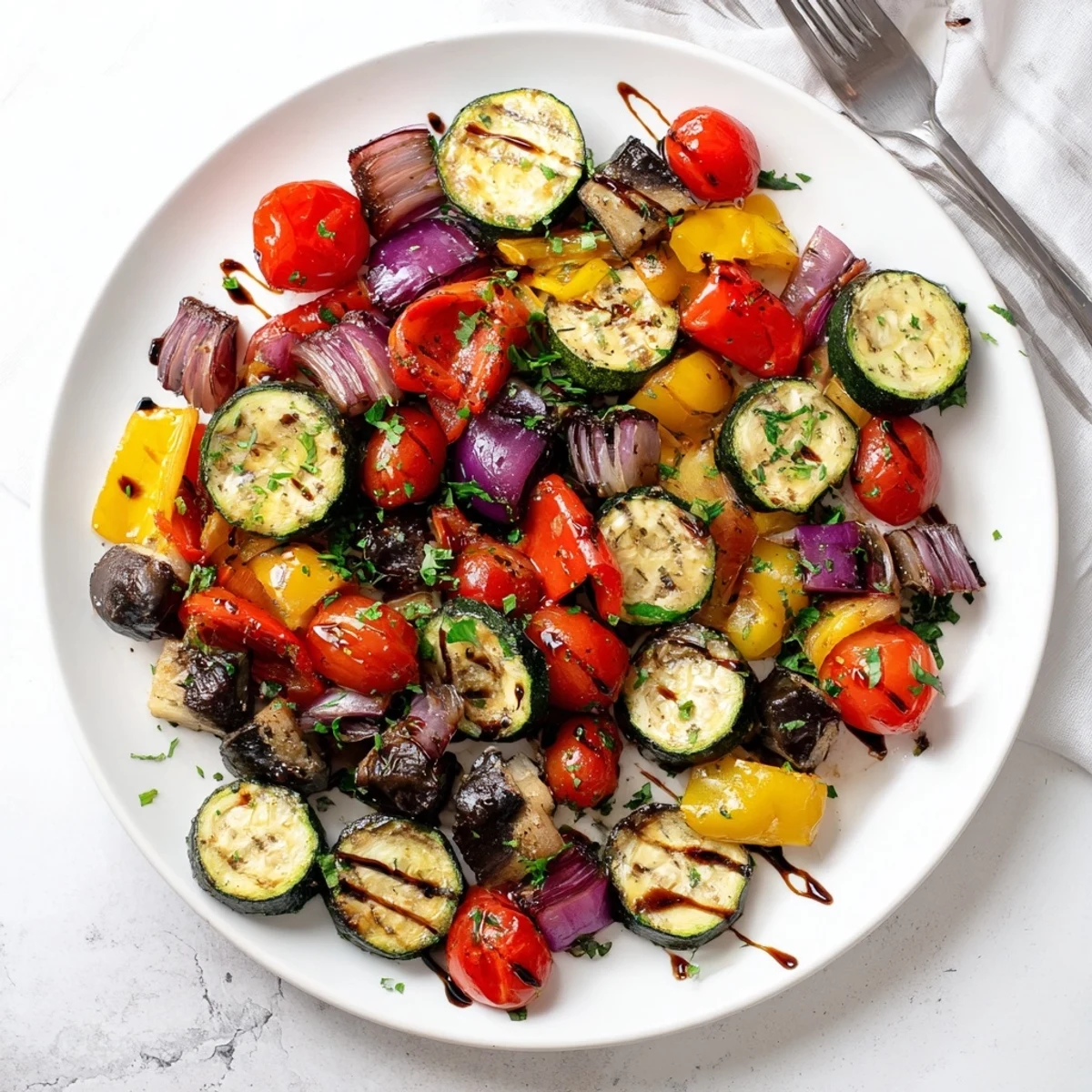 A close-up of Italian Roasted Vegetables with golden eggplant, red peppers, and glistening olive oil.