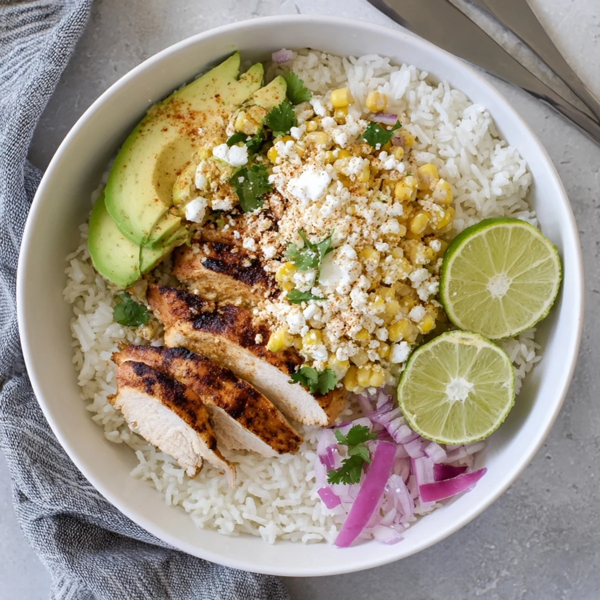 A close-up of Street Corn Chicken Rice Bowl with grilled chicken, charred corn, avocado, and cilantro garnish.