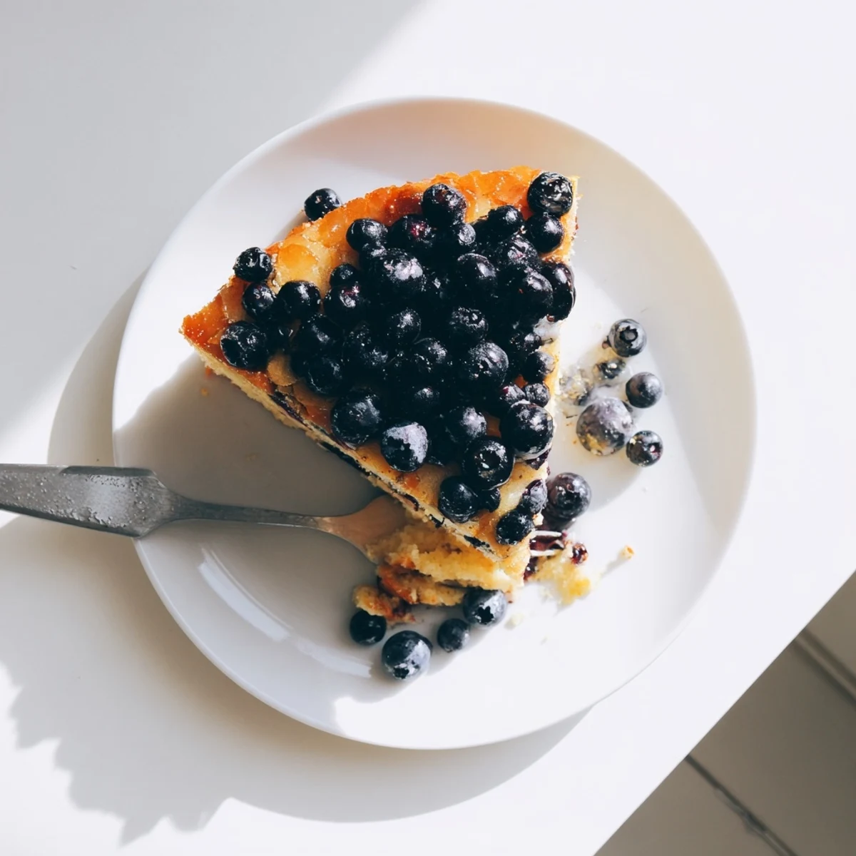 Slice of blueberry upside down cake revealing juicy caramelized berries and tender vanilla crumb