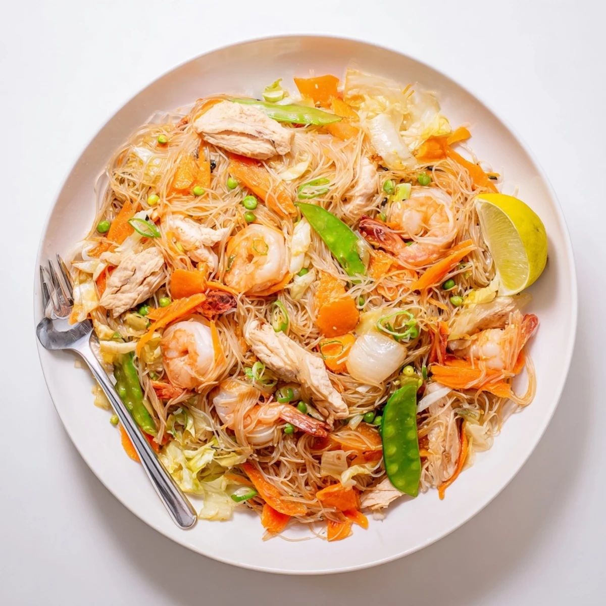 Steamy Filipino Pancit Bihon stir-fry featuring rice noodles, colorful vegetables, and savory soy-based sauce.