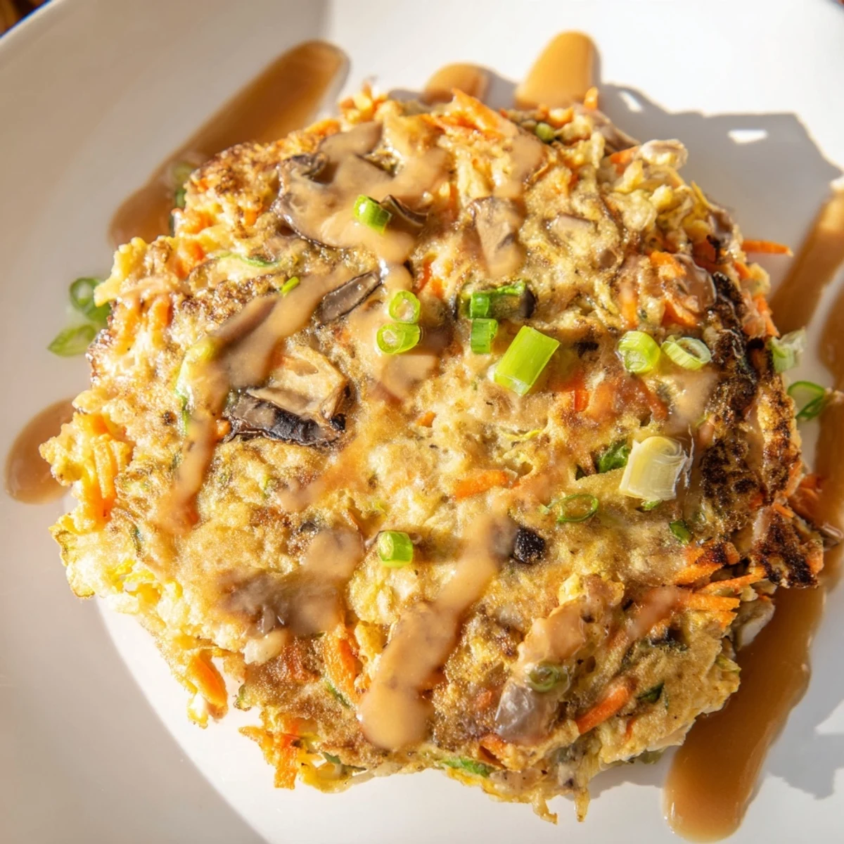 Chinese-American Egg Foo Young served hot with drizzled savory homemade sauce