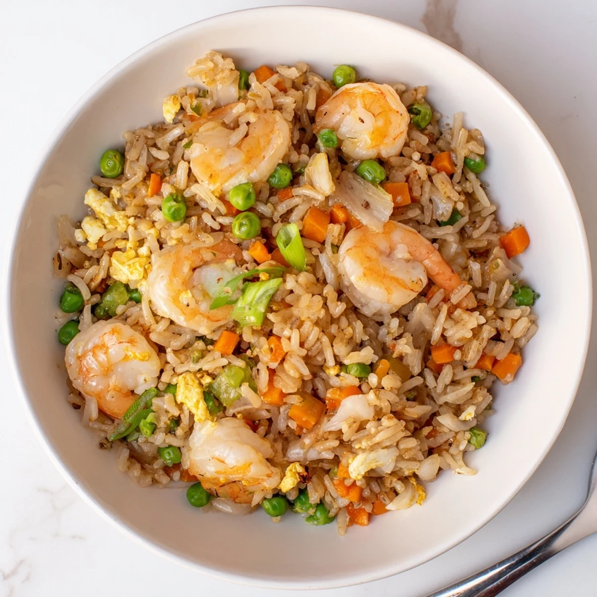 Golden authentic shrimp fried rice with colorful vegetables served in a white bowl