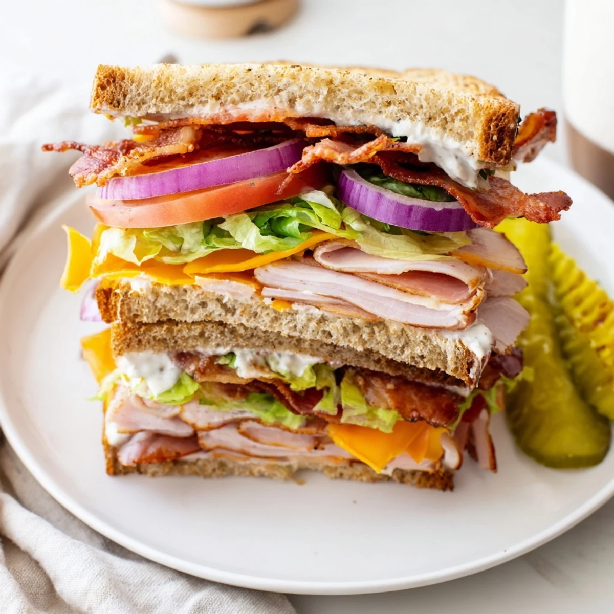 Stacked ultimate turkey beef bacon ranch sandwich with melted cheese, crisp vegetables, and ranch on toasted bread