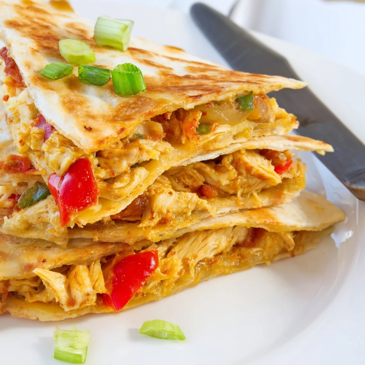 Golden baked chicken and cheese quesadillas cut into wedges on a white plate