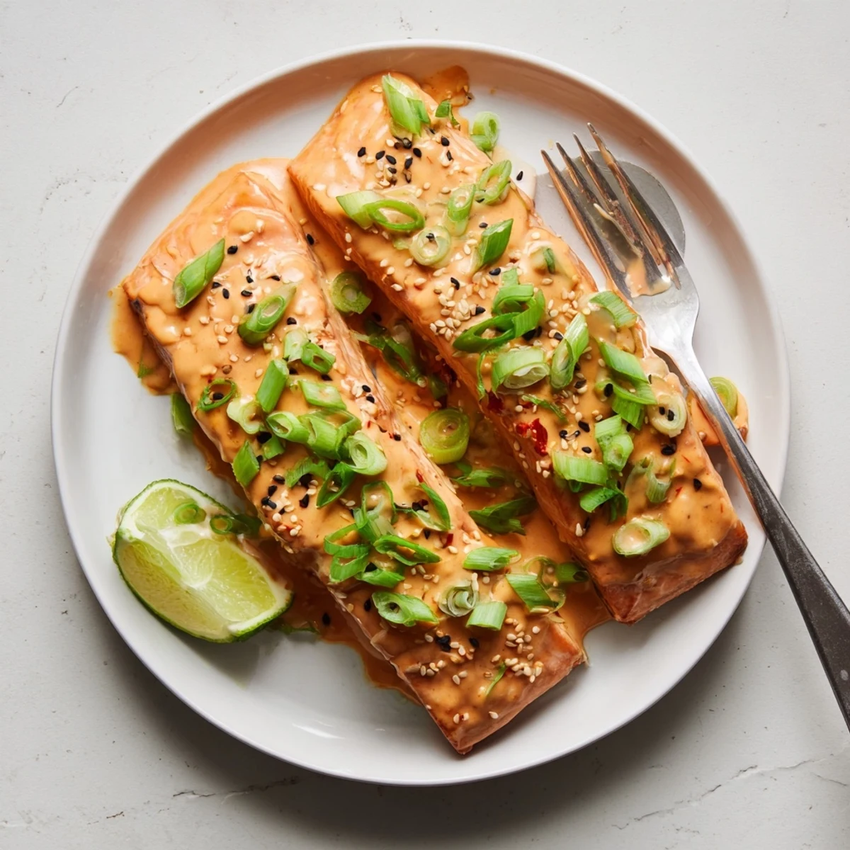 Golden baked Bang Bang salmon fillets glazed with creamy sweet spicy sauce and garnished with fresh green onions