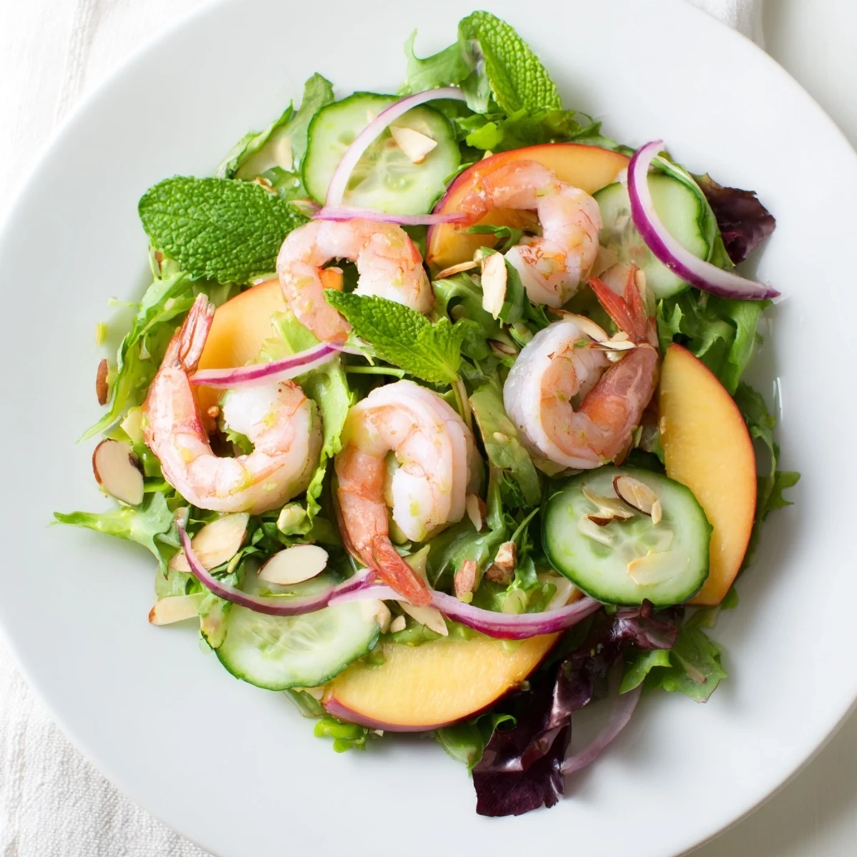 Vibrant summer salad featuring plump pink shrimp, ripe yellow nectarines, creamy avocado, and fresh mint garnish