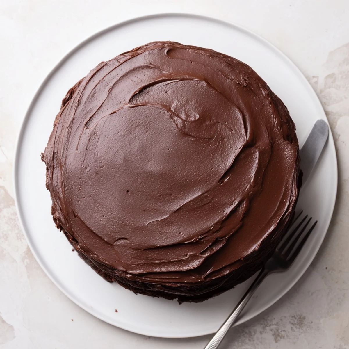 Rich layered chocolate cake frosted to perfection, sliced on a white serving plate
