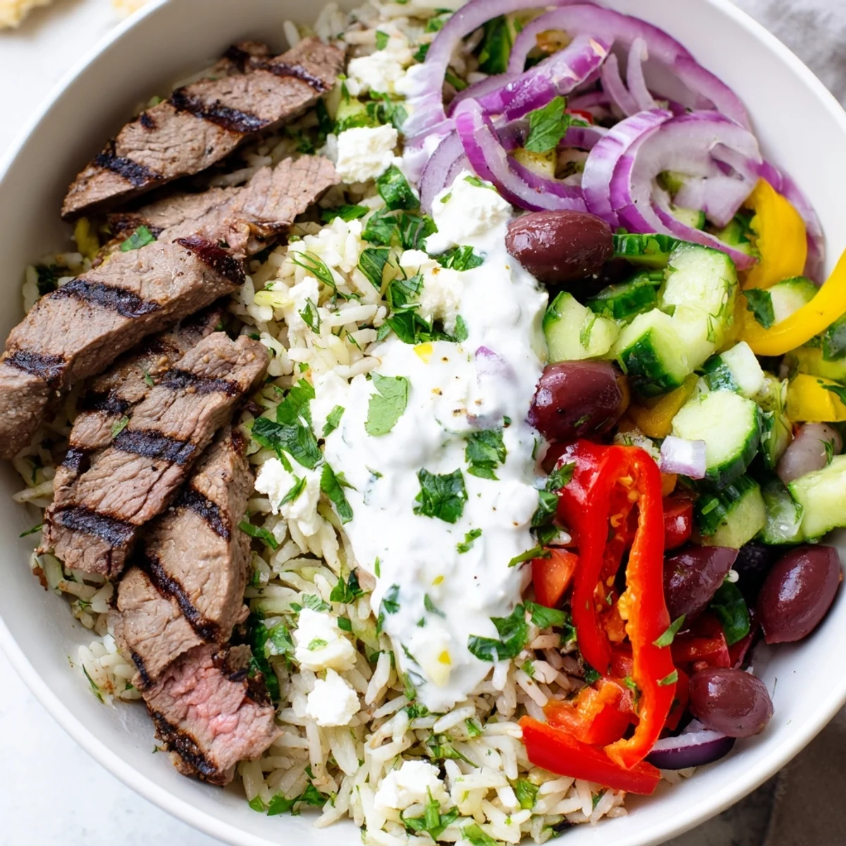 Protein-packed Mediterranean steak bowl featuring sliced flank steak, cherry tomatoes, olives, and crumbled feta cheese