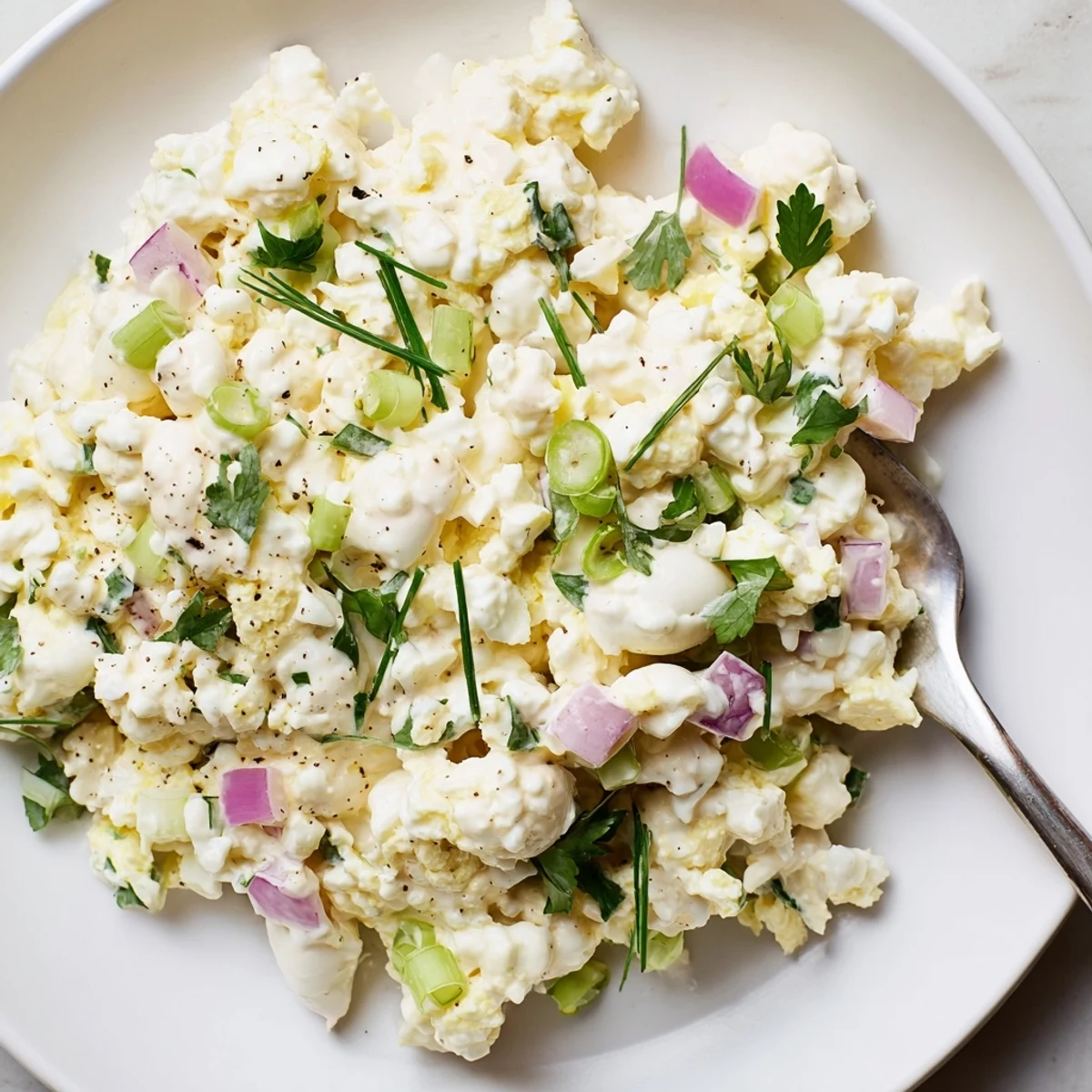 Creamy cottage cheese egg salad bowl topped with fresh chives and red onion