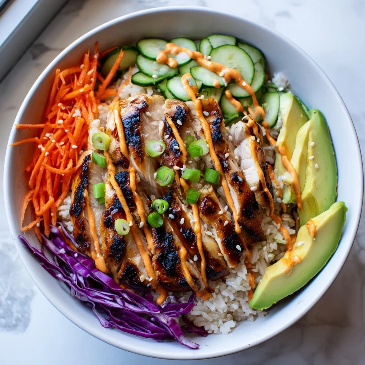 Sliced Korean BBQ chicken thighs arranged in meal prep bowls with fresh purple cabbage carrots and creamy spicy sauce