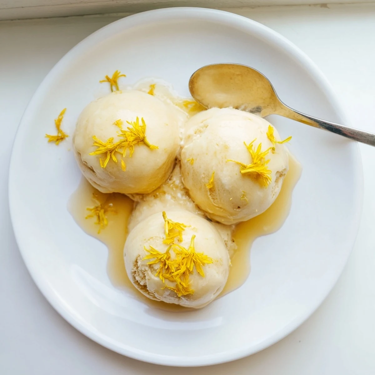 Floral dandelion honey ice cream served in glass bowl with shortbread cookie on side