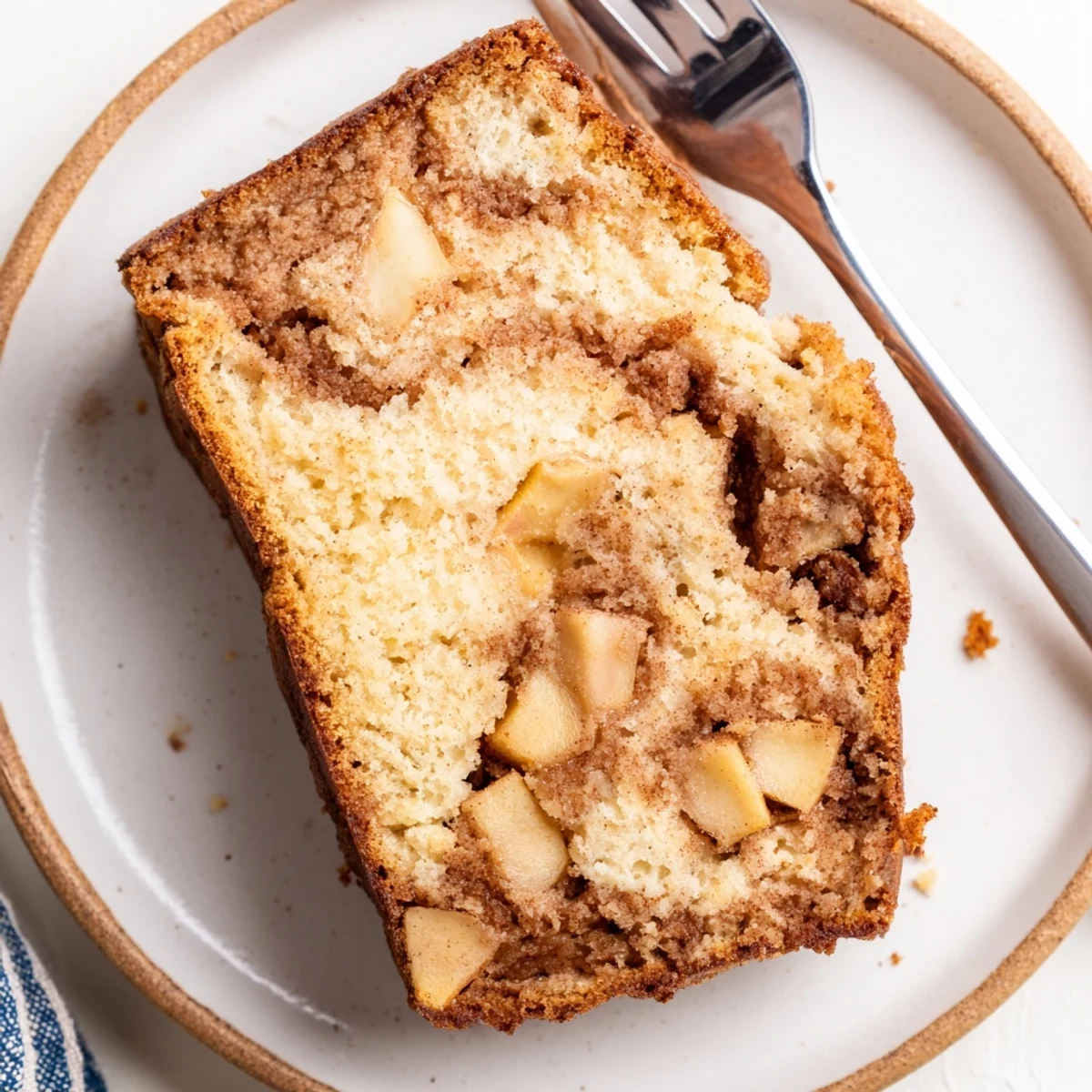 Golden cinnamon apple bread loaf with swirled sugar topping and juicy diced apple pieces throughout