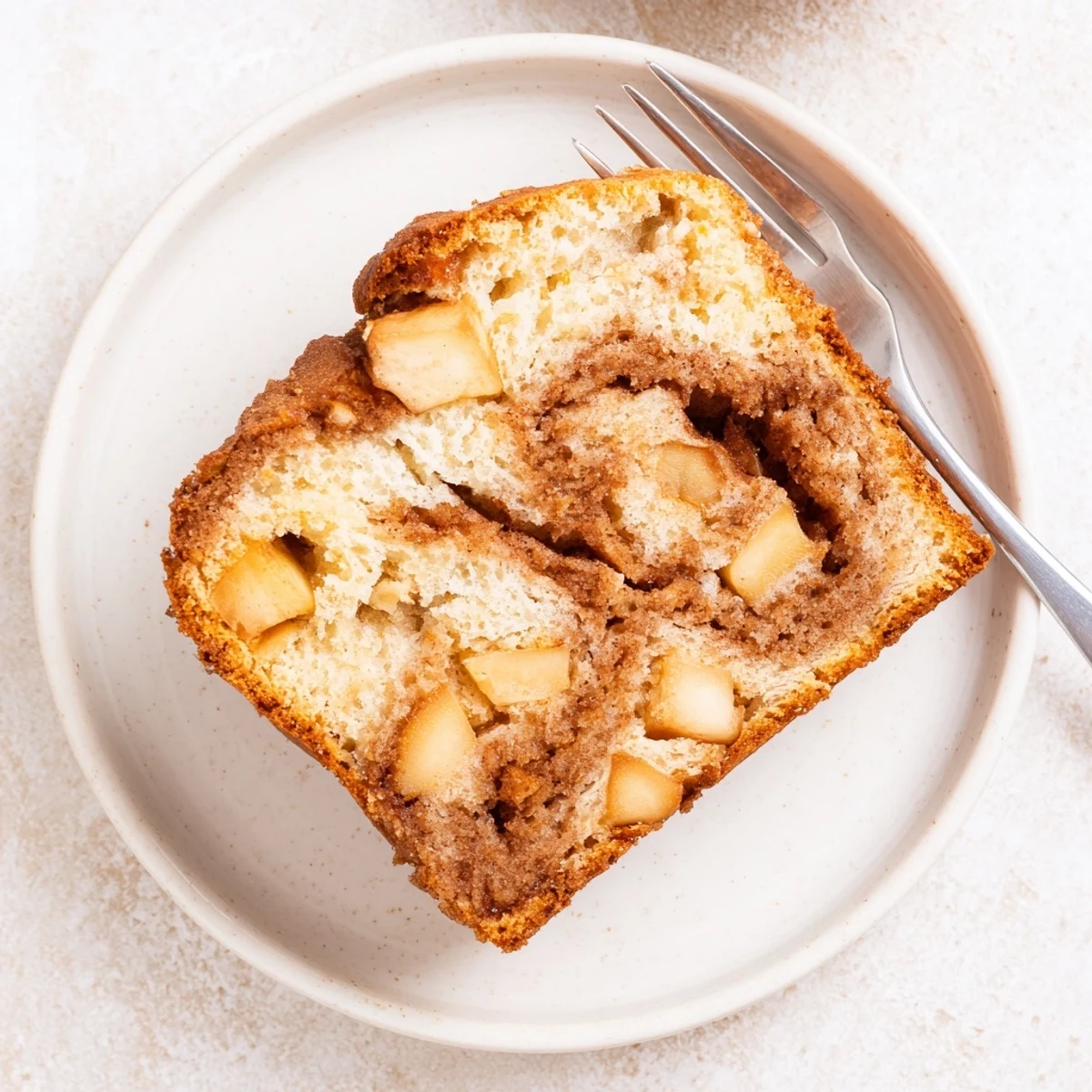 Freshly baked cinnamon apple bread cooling on wire rack with visible apple chunks and cinnamon swirl topping