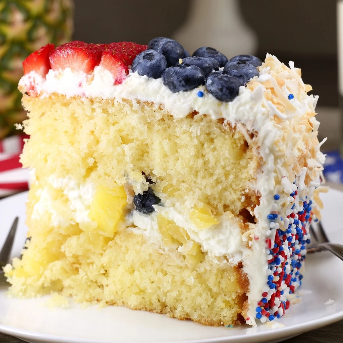 A slice of Pineapple Coconut God Bless America Cake showing creamy cream cheese frosting