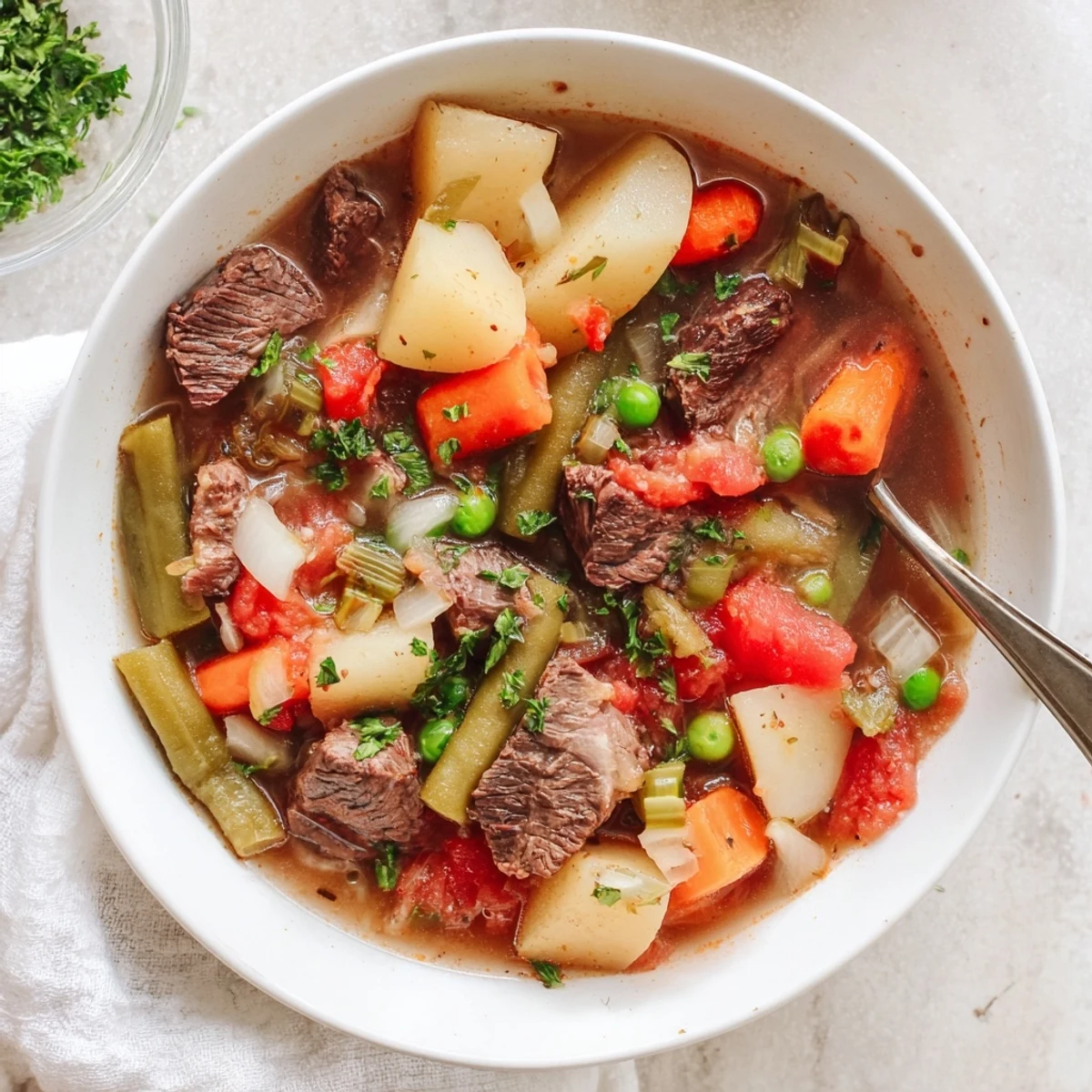 Steaming bowl of braised vegetable beef soup loaded with tender beef chunks, carrots, celery, and potatoes in rich savory broth