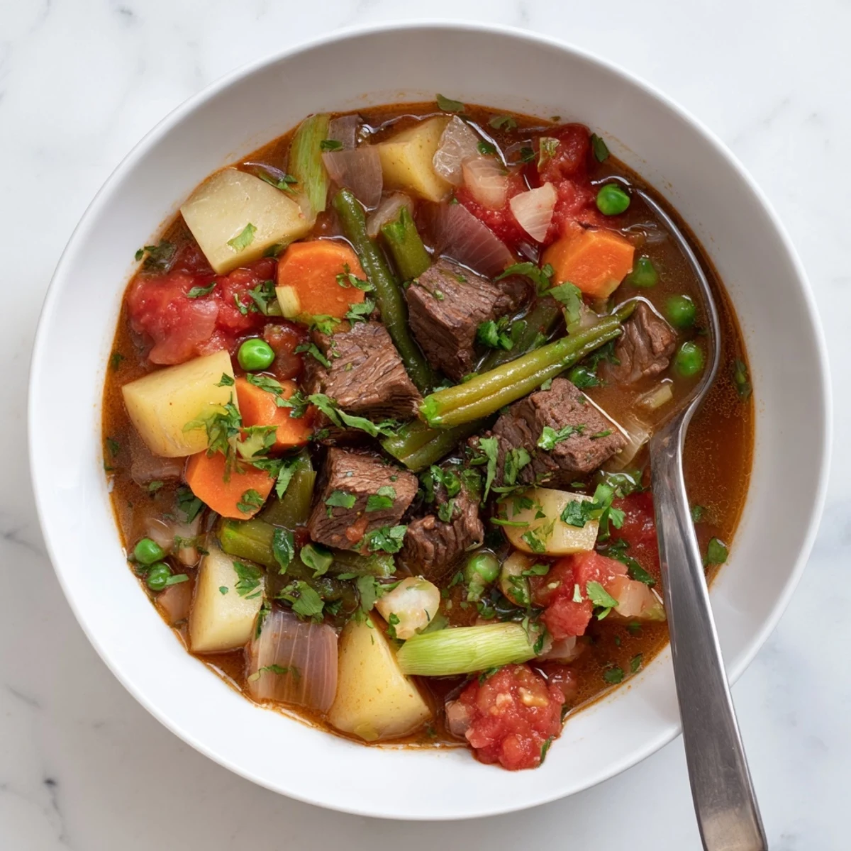 Hearty braised vegetable beef soup served in rustic white bowl with fresh parsley garnish and crusty bread on the side