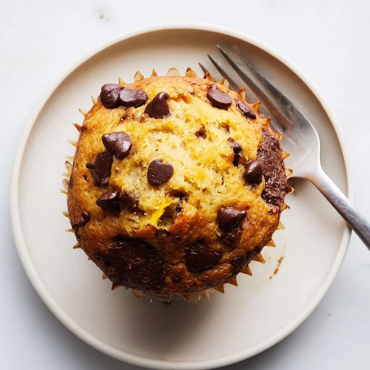 Freshly baked banana espresso chocolate chip muffins cooling on a wire rack with steaming coffee cup