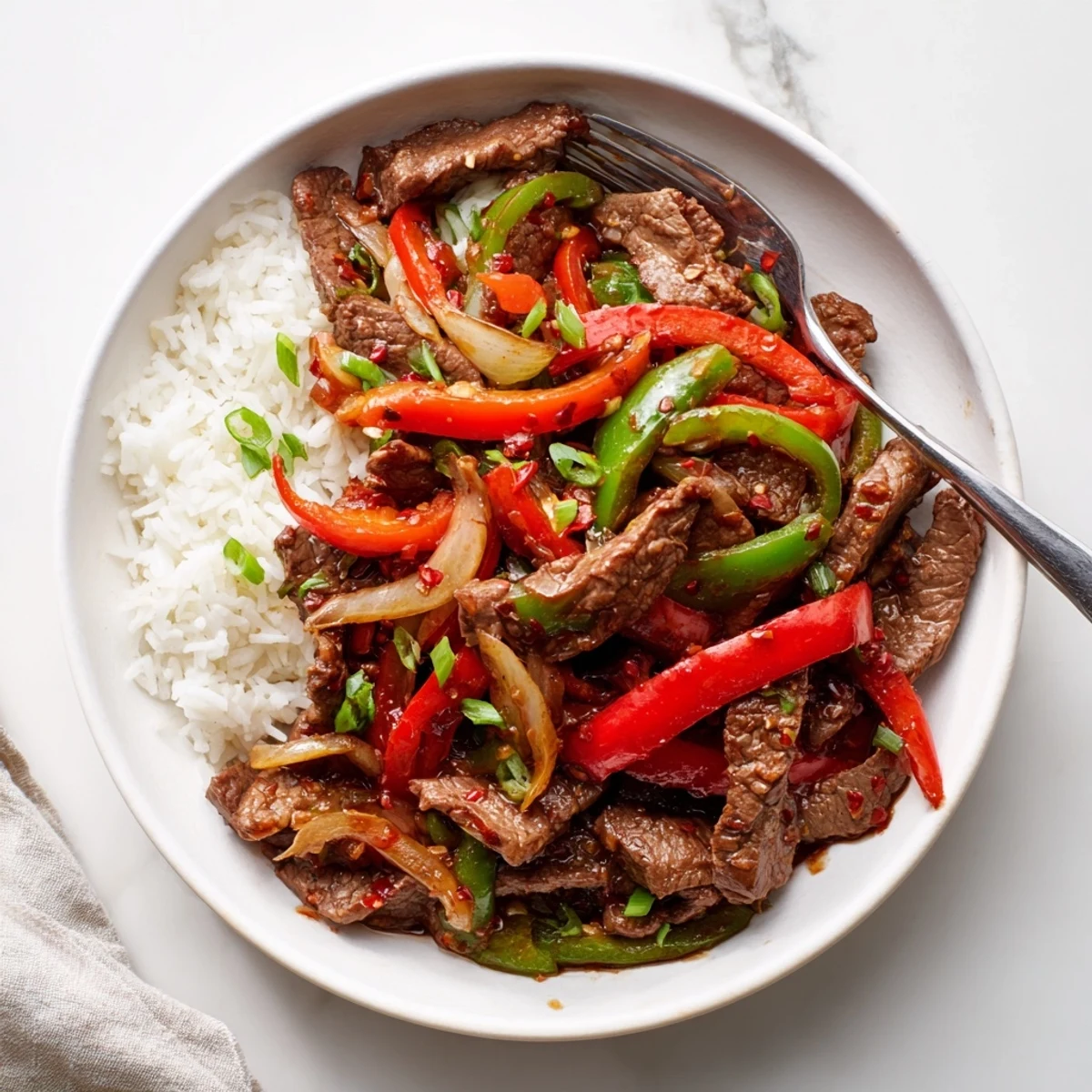 Sizzling spicy beef stir fry with chili garlic features tender beef strips and colorful crisp-tender bell peppers coated in a glossy fiery red sauce