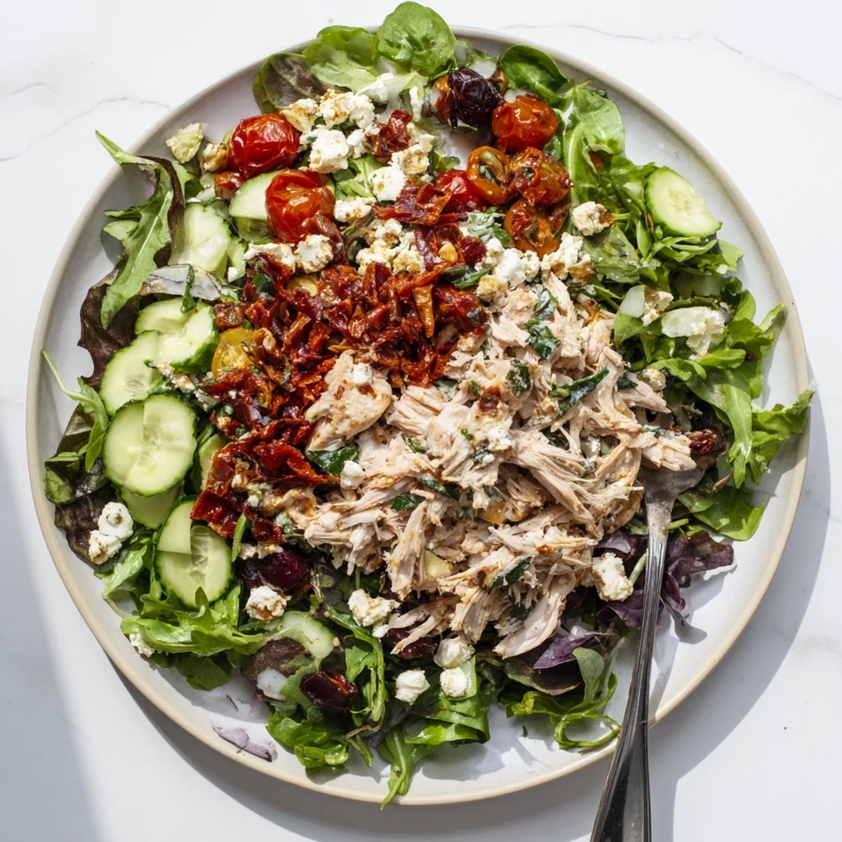 Colorful Mediterranean chicken salad bowl featuring tender meat, tangy sun-dried tomatoes, and crisp vegetables