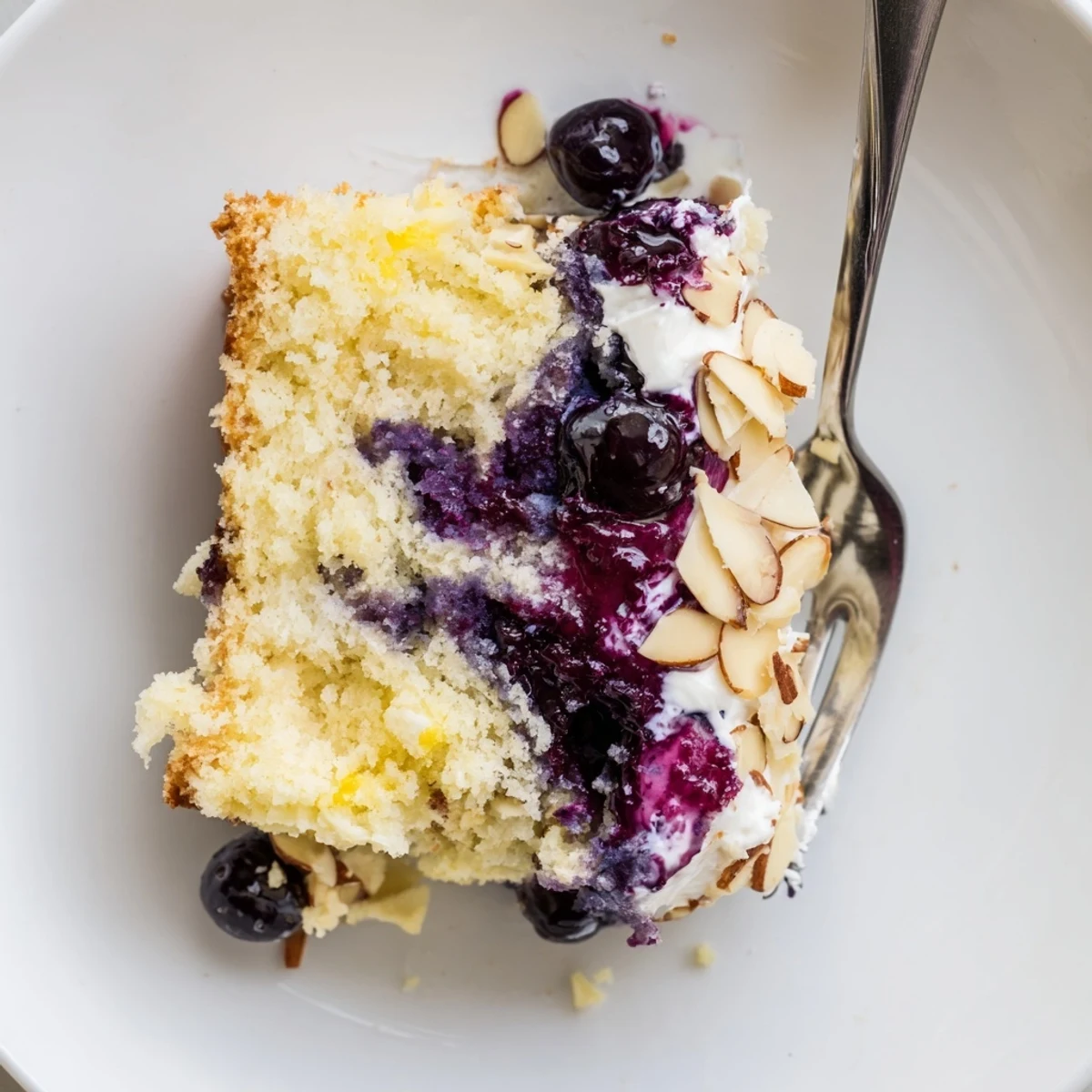 Lemon Blueberry Poke Cake With Almond Topping glistening with blueberry sauce and toasted almonds