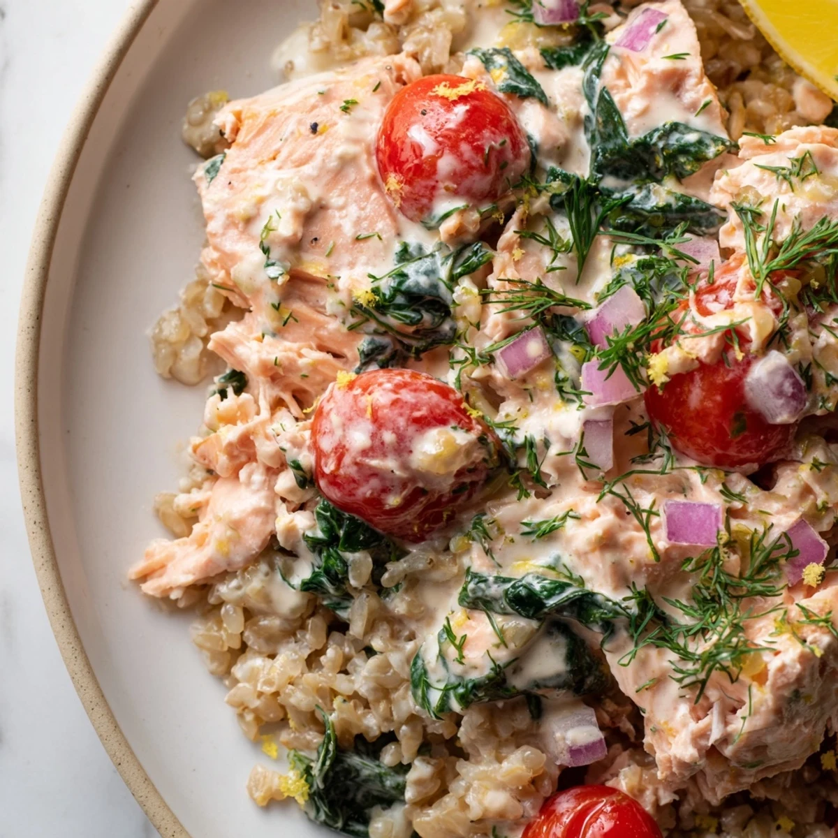 Bowl of creamy leftover salmon recipe garnished with parsley alongside whole wheat pasta