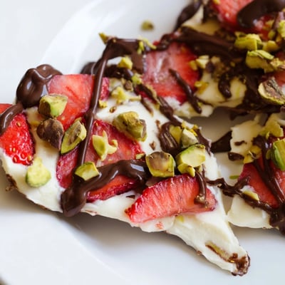 Melten dark chocolate is drizzled over the frozen yogurt and strawberry base for the Chocolate Covered Strawberry Yogurt Bark.