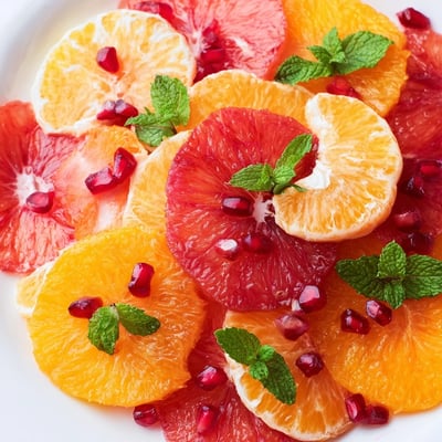 Freshly prepared Winter Citrus Fruit Salad in a glass bowl, featuring juicy citrus segments drizzled with glistening honey lime dressing.