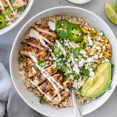 Freshly sliced Street Corn Chicken Bowl served over brown rice with cotija cheese and lime wedges.