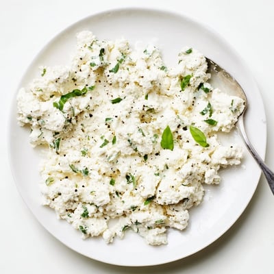 A bowl of homemade Tofu Ricotta with a lemon wedge and olive oil drizzle.