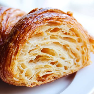 Freshly baked Gluten-Free Croissants dusted with powdered sugar, served warm with jam on a rustic wooden table.