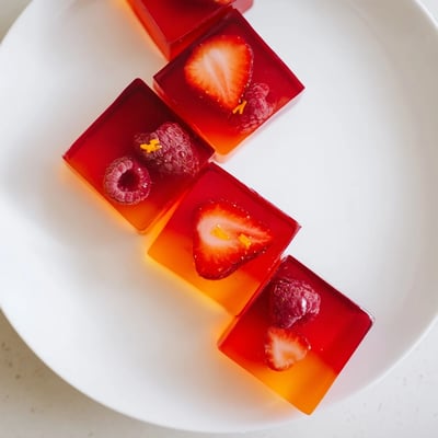 Colorful homemade collagen fruit jellies arranged on a clean white serving board